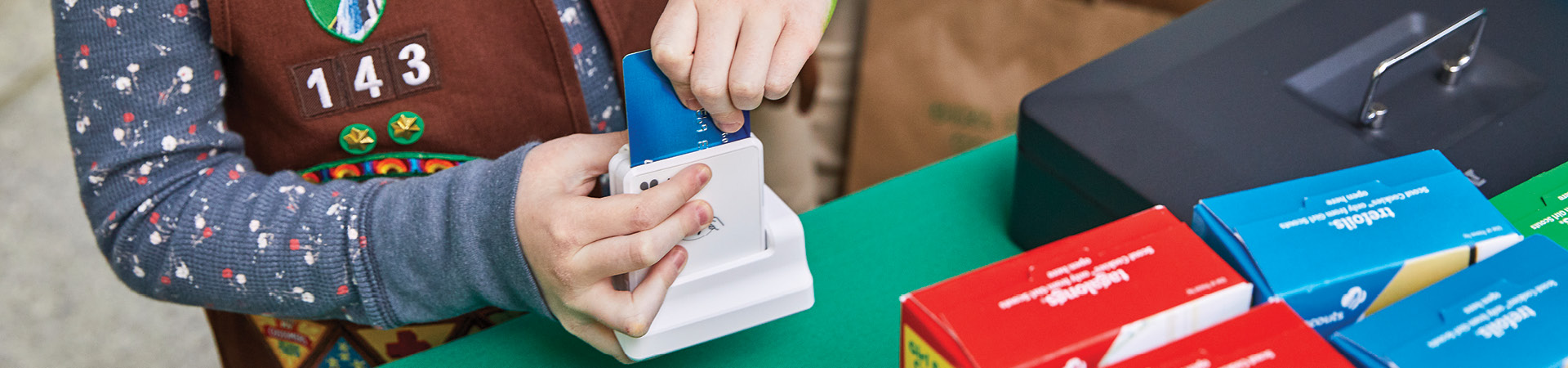  A Girl Scout scanning a customer's credit card at a cookie booth 