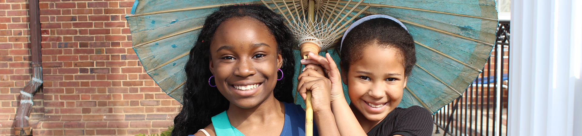  Two young girls stand under an umbrella 