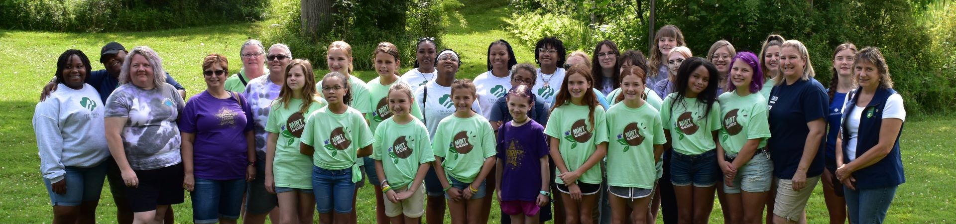  A group of Girl Scouts and volunteers of all ages outdoors 