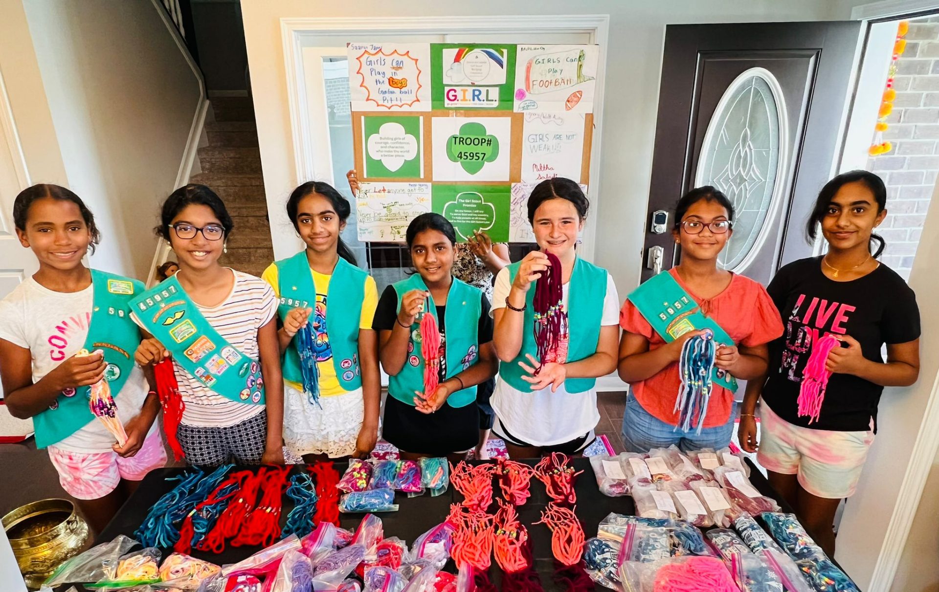  7 Girl Scout Juniors stand in front of the items they crocheted.  