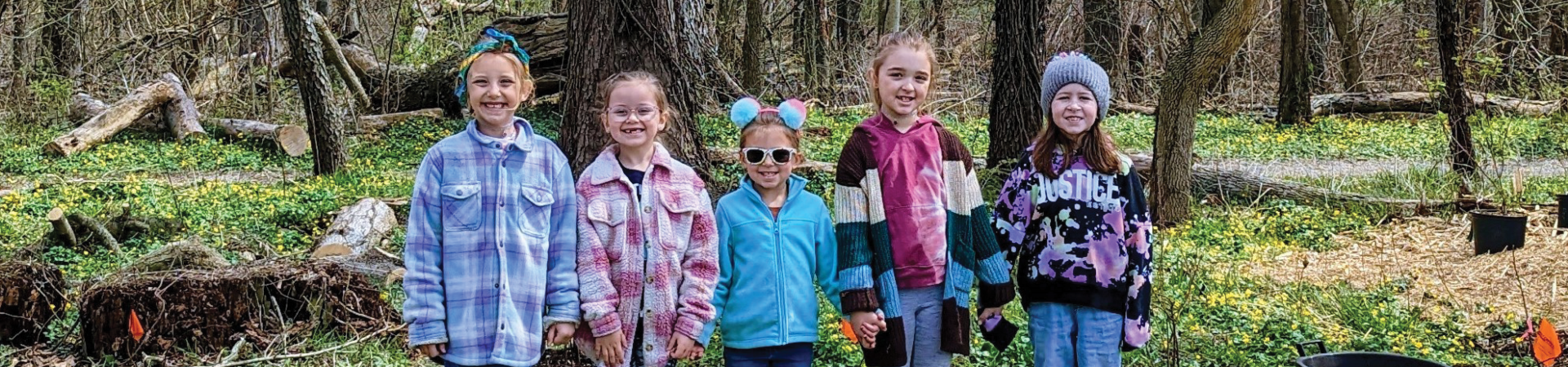  Five Girl Scouts stand in the forest. 