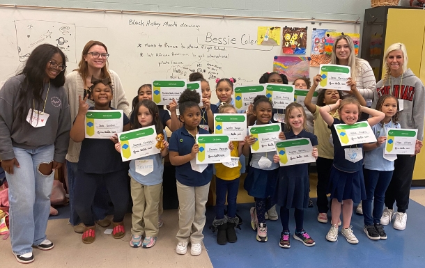 All 4 Girl Scout volunteers stand with a large group of girls proudly holding awards.