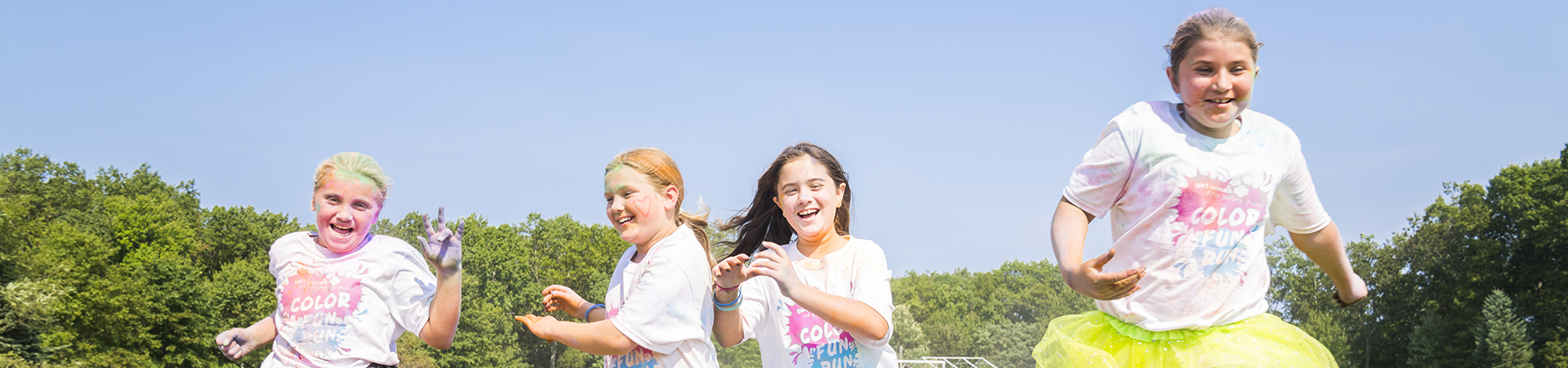  Four young girls run toward the camera covered in colored dust 