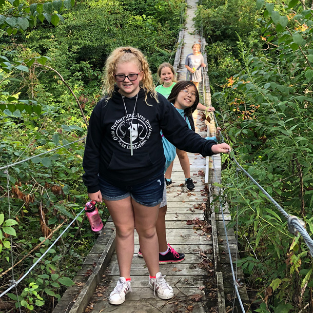 A group of girls walking across a swinging bridge