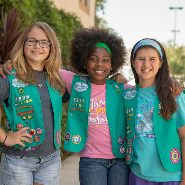 Three Junior Girl Scouts with their arms around each other