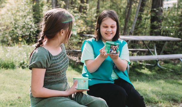 Two girls looking at tin containers of nuts and candy products