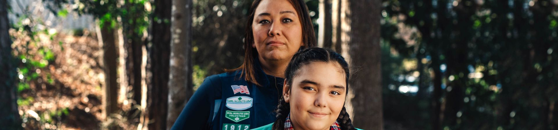  A volunteer standing behind a Girl Scout outdoors 