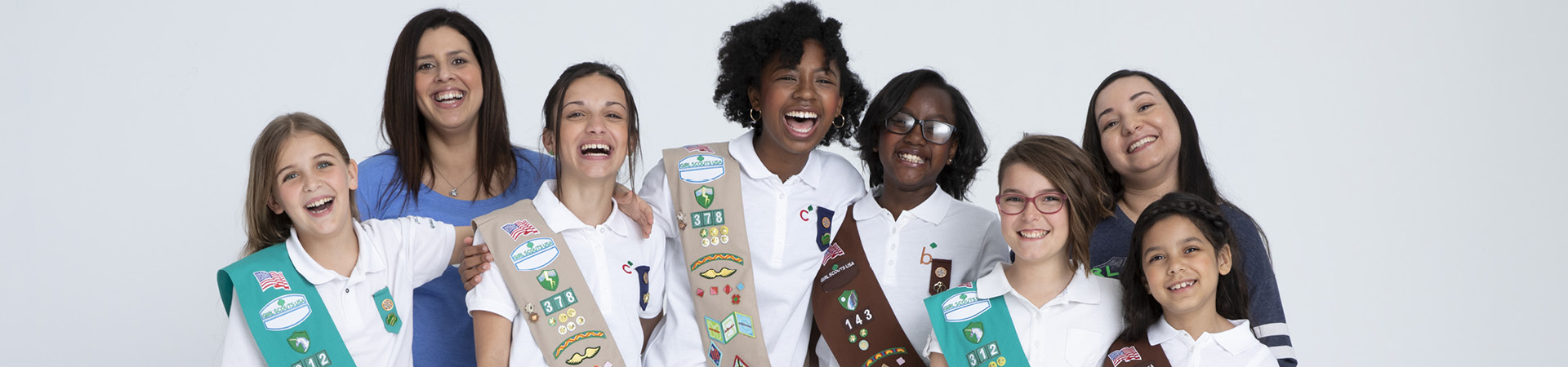  A diverse group of Girl Scouts smiling with two leaders 