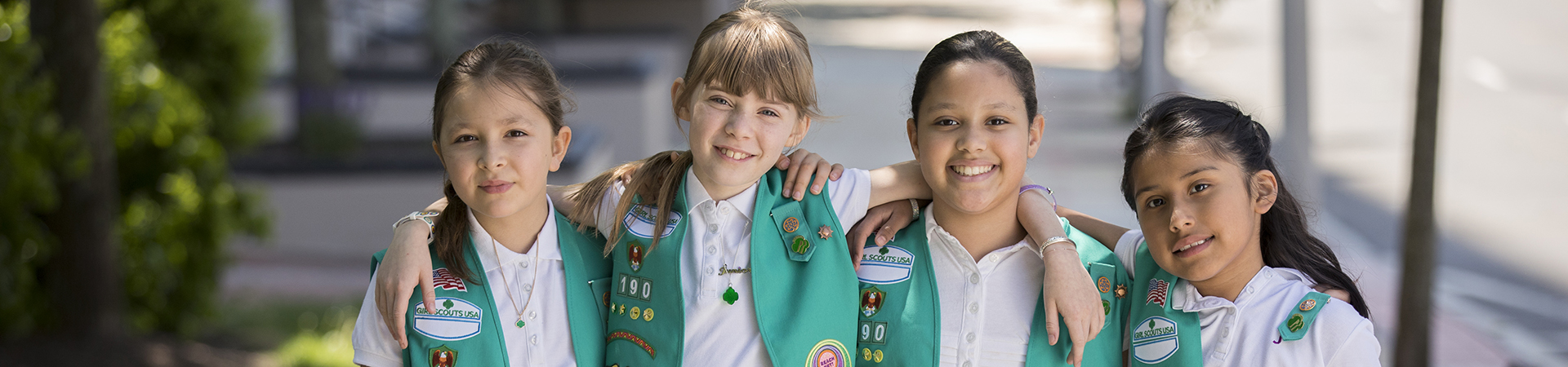  A group of Girl Scouts smiling with their arms around each other 