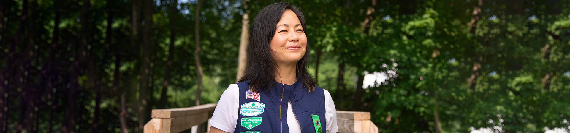  Volunteer stands on a wooden platform in the forest looking off into the distance 